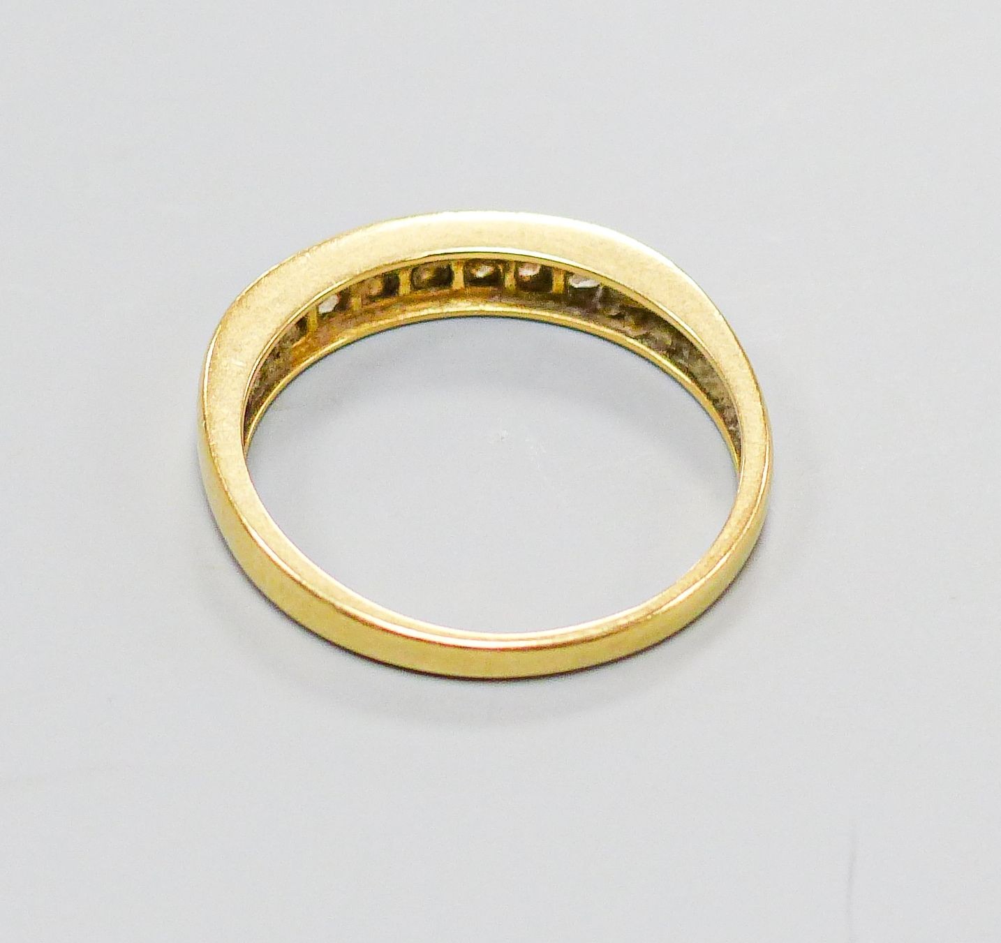 A modern 18ct gold and channel set seven stone diamond half hoop ring, size P, gross weight 2.8 grams.